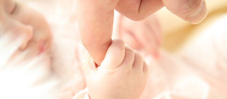 baby holding person s index finger